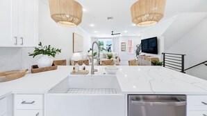 A modern kitchen with white cabinetry, a large island with a sink, two pendant lights, and a built-in dishwasher. - Luxury, Blue Eden Bliss Sleeps 12, Close to Bay (Santa Rosa Beach)