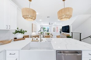 A modern kitchen with white cabinetry, a large island with a sink, two pendant lights, and a built-in dishwasher. - Luxury, Blue Eden Bliss Sleeps 12, Close to Bay (Santa Rosa Beach)