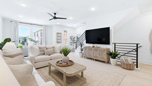 A modern living room with a sofa, coffee table, TV, and plants. - Luxury, Blue Eden Bliss Sleeps 12, Close to Bay (Santa Rosa Beach)