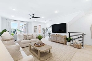 A modern living room with a sofa, coffee table, TV, and plants. - Luxury, Blue Eden Bliss Sleeps 12, Close to Bay (Santa Rosa Beach)