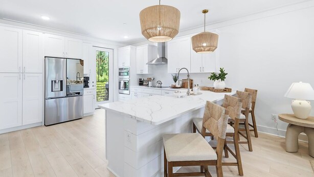A modern kitchen with white cabinetry, stainless steel appliances, a central island, and wicker chairs. - Luxury, Blue Eden Bliss Sleeps 12, Close to Bay (Santa Rosa Beach)