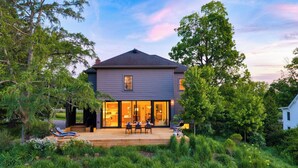 A two-story house with a deck, surrounded by lush greenery. - River View by Avantstay Arch Digest 1863 Italianate + Pool + Screening Room Hudson Views (Germantown)