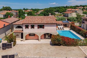 Eine Villa mit Swimmingpool, steinernen Bögen und einem roten Ziegeldach.