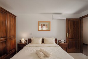 Ein Schlafzimmer mit einem Bett, zwei Nachttischen, einem Schrank, einem Bilderrahmen an der Wand und einer Tür.