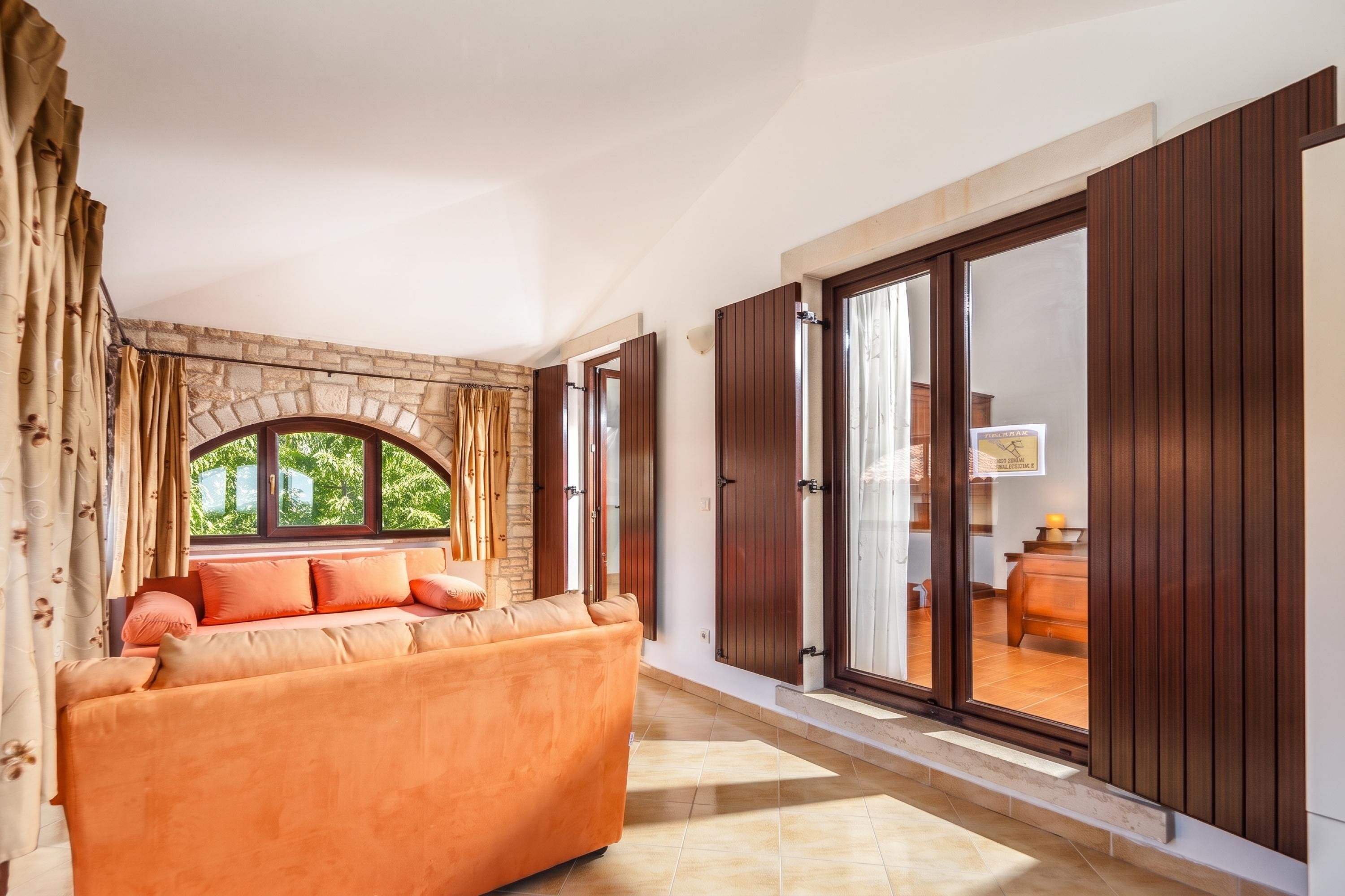 A hallway with a sofa, a stone wall, and a large window.