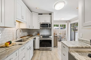 A modern kitchen with white cabinets, a stainless steel sink, a built-in microwave, and a double oven. - Sea Pines 3BR, Pet-Friendly, South Beach Pool Access, Bike to Beach & Golf! (Hilton Head Island)