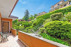 A residential building with a balcony, a wooden door, and a staircase leading to a green garden. - Riflessi Di Luce: Lake Maggiore View Balcony Stresa, Stresa, Italy (Stresa)
