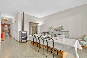 A dining room with a long table, chairs, a stove, and a chandelier. - Riflessi Di Luce: Lake Maggiore View Balcony Stresa, Stresa, Italy (Stresa)