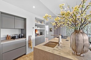 Eine moderne Küche mit grauen Schränken, einer großen Kochinsel mit Spüle und einer Blumenvase.