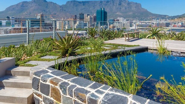 Une piscine sur le toit, avec une vue sur la ville et les montagnes en arrière-plan.