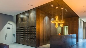 Un hall d’entrée moderne avec un comptoir d’accueil, un mur de casiers et un luminaire original.