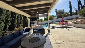 Une terrasse extérieure couverte avec une piscine, un espace salon et une vue sur le paysage environnant.