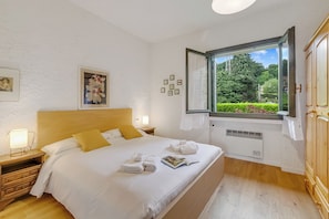 A neatly made bed with white linens, a wooden headboard, and a window with a view of greenery. - Oasi nel Parco - Hillside Home with Shared Pool, Gignese, Italy (Gignese)