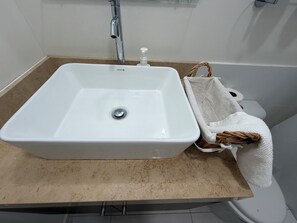 A bathroom with a white sink, a towel, and a toilet. - Studio apartment (San Miguel)