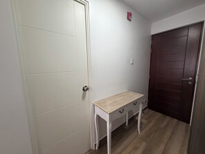 A hallway with a white door, a wooden bench, and a dark wooden door.