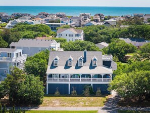 A coastal residential area with houses, a prominent house with a balcony, and a view of the ocean. - The Virginian at Duck - Sound Sea Village, Sound Views, Private Dock, Pets OK, Flex Stays (Duck)