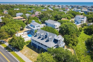 An aerial view of a residential area with houses, a swimming pool, and a road. - The Virginian at Duck - Sound Sea Village, Sound Views, Private Dock, Pets OK, Flex Stays (Duck)