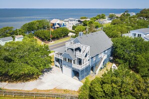 A coastal house with a prominent front porch, a garage, and a view of the sea. - The Virginian at Duck - Sound Sea Village, Sound Views, Private Dock, Pets OK, Flex Stays (Duck)