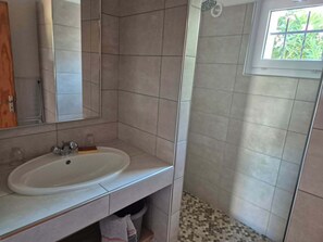 A bathroom with a sink, mirror, and shower. - MINI Villa in Santa Giulia 4 (Porto-Vecchio)