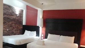 Een hotelkamer met twee bedden, een geaccentueerde bakstenen muur, een rode accentmuur en een plafondlamp.