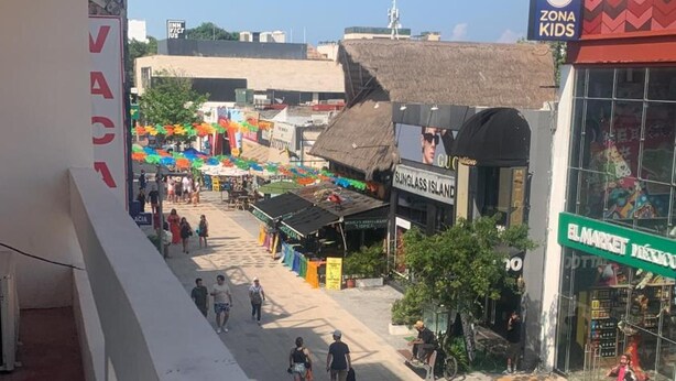 Straatbeeld met een marktgebied, een gebouw met een bord waarop 'SUNGLASS ISLAND' staat, en een winkel met de naam 'EL MARKET'.
