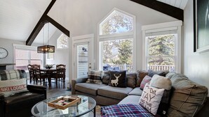 A living room with a sofa, a coffee table, and a dining area with chairs and a table. - Downtown Breckenridge retreat with mountain views, fireplace, hot tub. (Breckenridge)