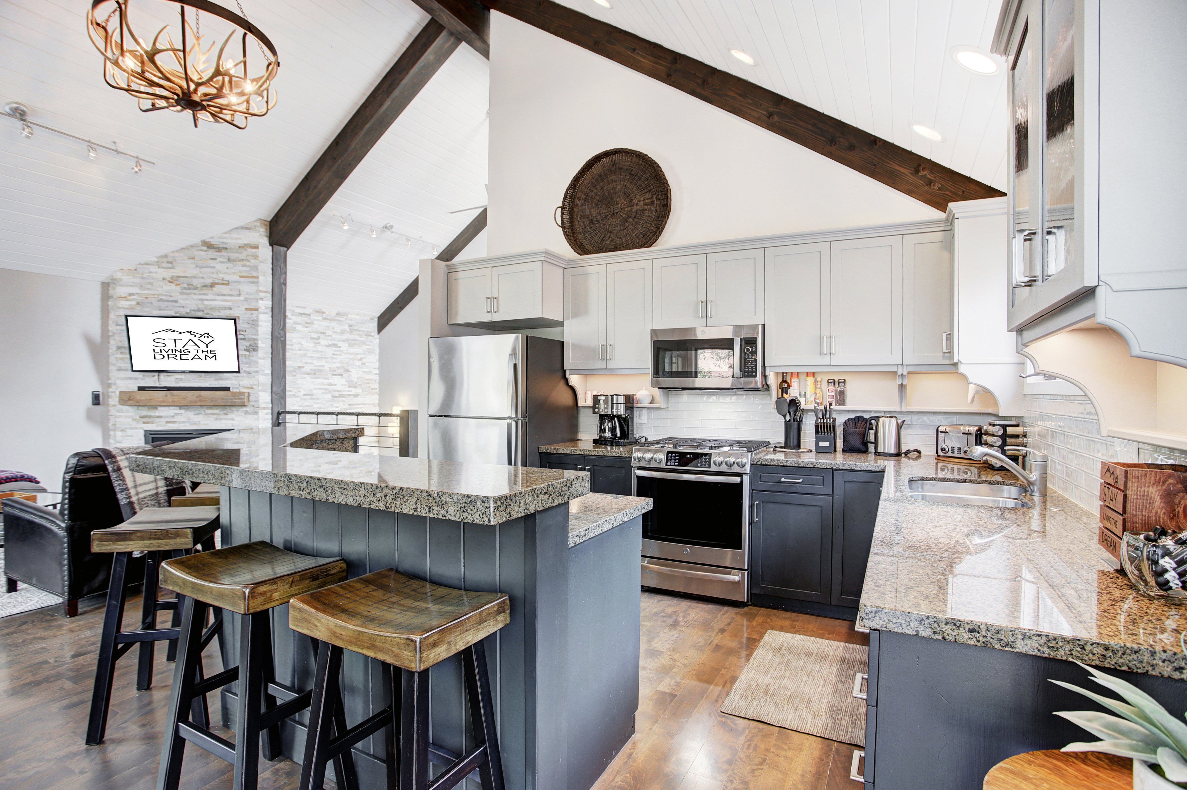 A modern kitchen with granite countertops, stainless steel appliances, and a bar area with stools.