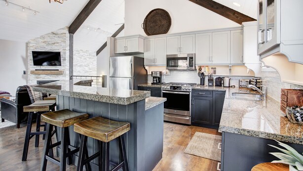 A modern kitchen with granite countertops, stainless steel appliances, and a large island with bar stools. - Downtown Breckenridge retreat with mountain views, fireplace, hot tub. (Breckenridge)