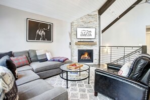 A modern living room with a stone fireplace, a sofa, a coffee table, and a black leather armchair. - Downtown Breckenridge retreat with mountain views, fireplace, hot tub. (Breckenridge)