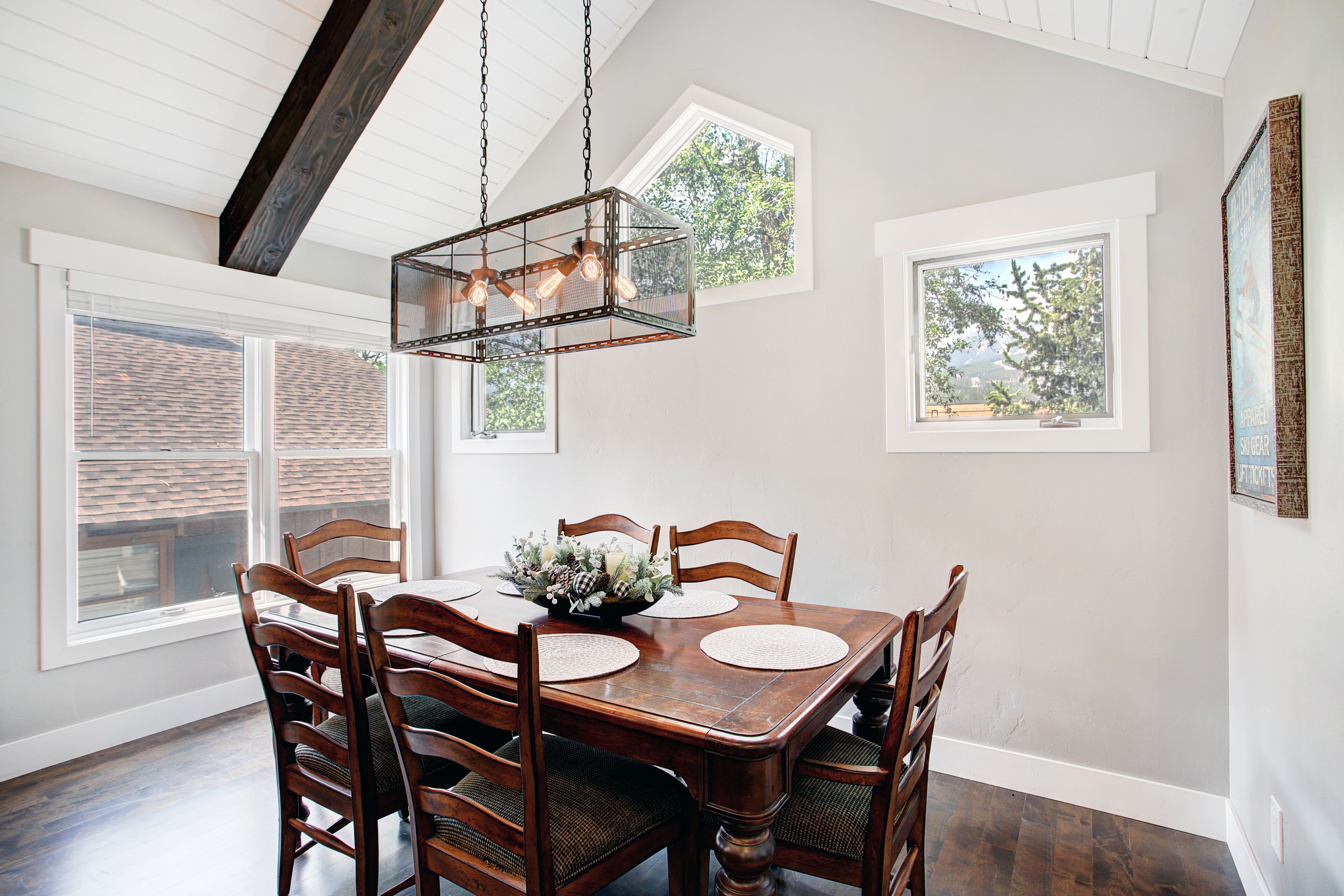 A dining room with a wooden table, chairs, and a hanging light fixture.