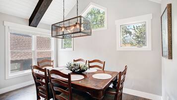 A dining room with a wooden table, chairs, and a hanging light fixture.