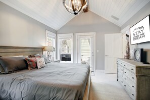 A bedroom with a large bed, a dresser, a chandelier, and a motivational poster. - Downtown Breckenridge retreat with mountain views, fireplace, hot tub. (Breckenridge)