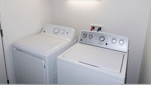 Ein Waschraum mit zwei weißen Waschmaschinen und einem Trockner, einem Schrank darüber und einer Wandleuchte.
