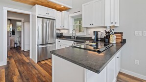 Una cocina moderna con armarios blancos, electrodomésticos de acero inoxidable y techo de madera.