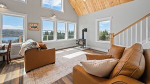 Un salón comedor amplio con techo alto, ventanas grandes, chimenea y una zona de estar acogedora.