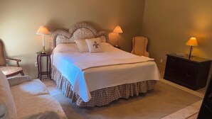 Een keurig opgemaakt slaapkamer met een groot bed, twee nachtkastjes, een stoel en een dressoir.