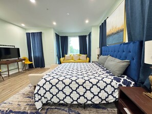 Ein Schlafzimmer mit einem großen Bett, einem Fernseher, einem Schreibtisch und einem Sofa.