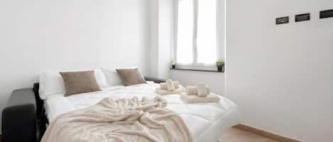 A bedroom with a bed, a window, a bedside table, and a wall-mounted shelf with plants.