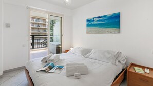 Ein Schlafzimmer mit Bett, Nachttisch, Gemälde und Blick auf einen Balkon.