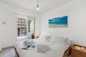 Ein Schlafzimmer mit Bett, Nachttisch, Gemälde und Blick auf einen Balkon.
