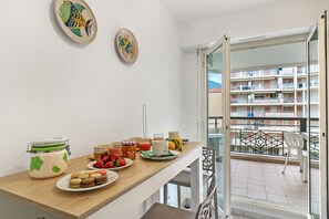 A balcony with a view of a building, a dining table with food and drinks, and two decorative plates on the wall. - Daturas Bright Apt with Balcony, Menton, France (Menton)