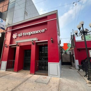 Un edificio rojo con un letrero que dice 'El TeapaneCo' y una entrada protegida por una reja.