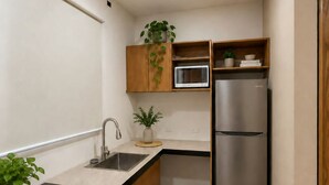 A compact kitchen with a built-in microwave, a stainless steel refrigerator, and a wooden cabinet with a plant. - LOFT. 5 Next to CERACOM and 500 m from Plaza Crystal. (Villahermosa)