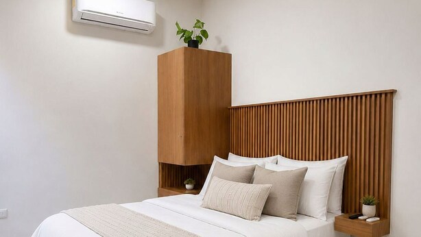 A bedroom with a bed, a wooden headboard, a bedside table, a nightstand, an air conditioner, and a potted plant. - LOFT. 5 Next to CERACOM and 500 m from Plaza Crystal. (Villahermosa)