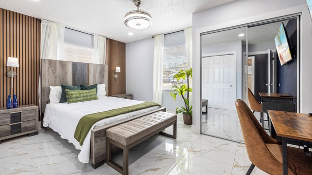Een moderne hotelkamer met een bed, een bankje, nachtkastjes, een bureau en een stoel.