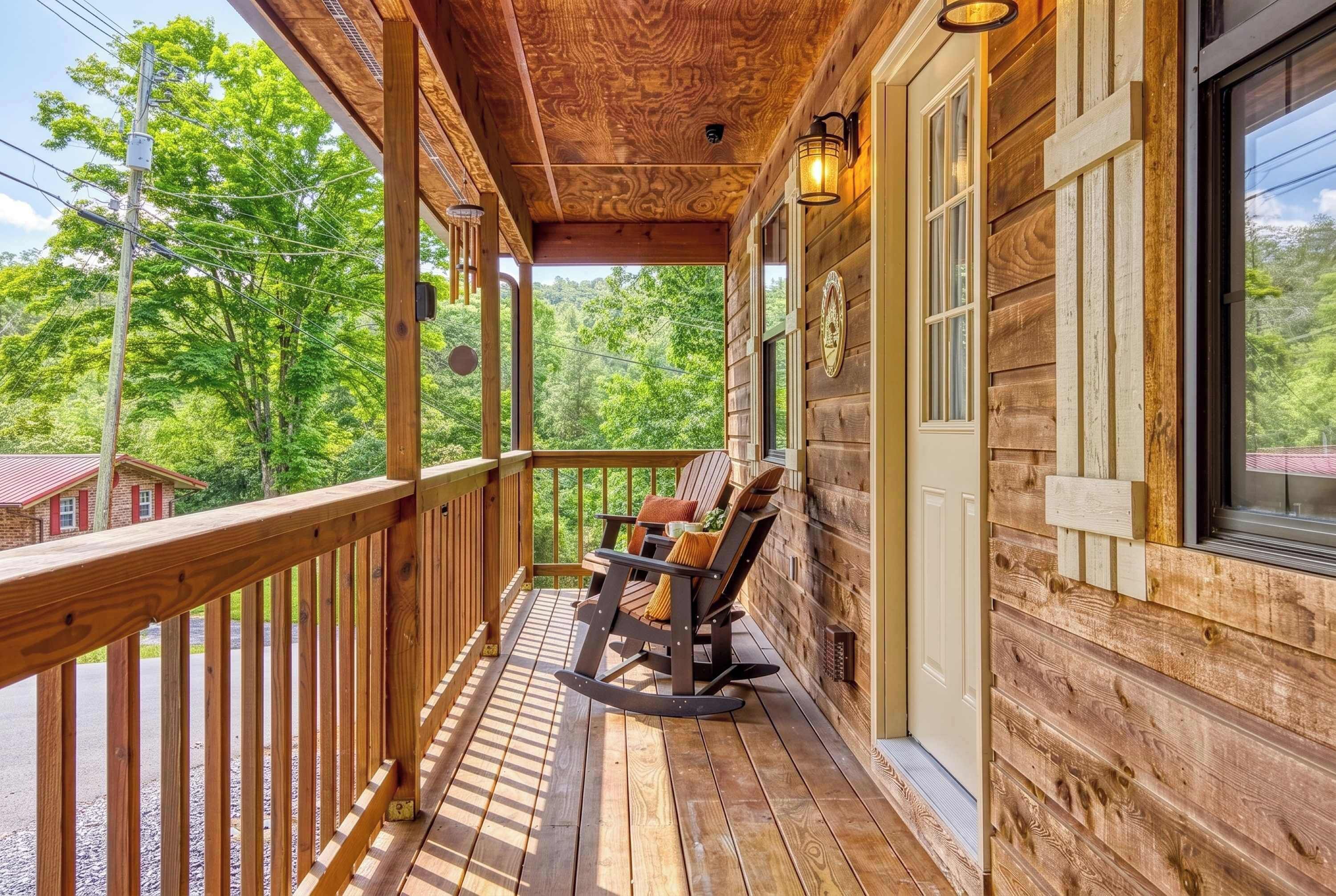 A wooden porch with a rocking chair and a table, overlooking a forested area.