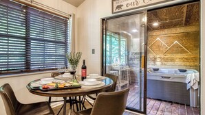 Un comedor con una mesa dispuesta para cuatro personas, un jacuzzi y un cartel que dice 'Bienvenidos a nuestra cabaña'.