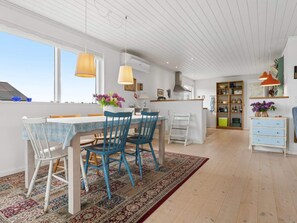 A modern kitchen with a dining area, large windows, and a view of the sky. - 4 Star Holiday Home in Bogense (Bogense)