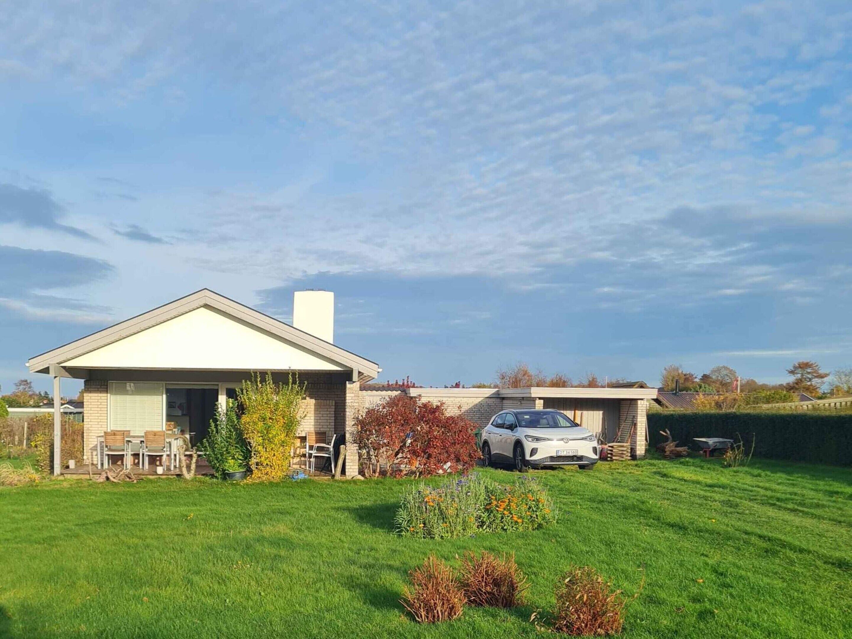 Una casa a un piano con garage, prato e un'auto parcheggiata davanti.