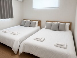 Two single beds with wooden headboards, white linens, and grey pillows.